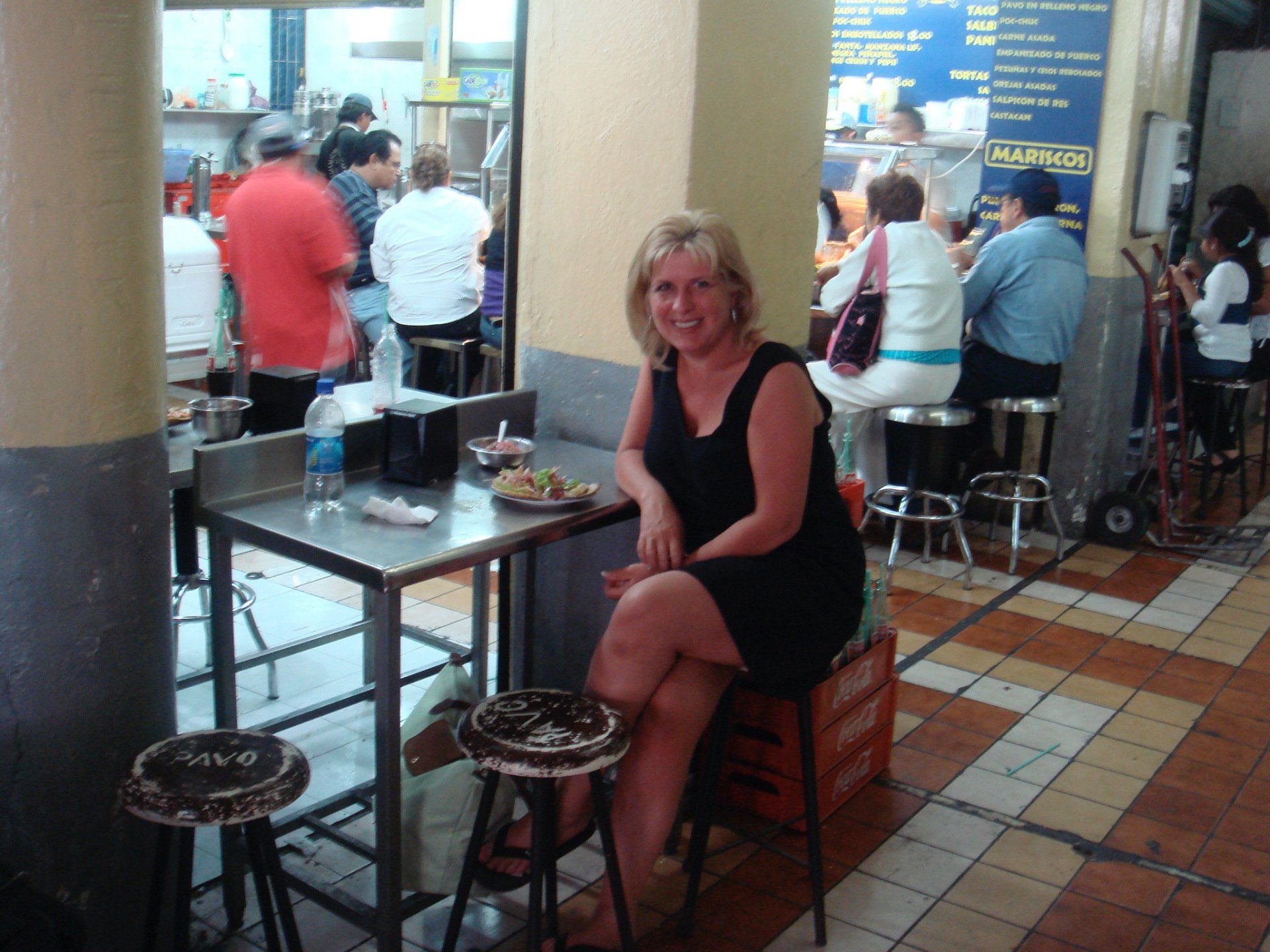 A woman in a black dress sits at a table in a restaurant