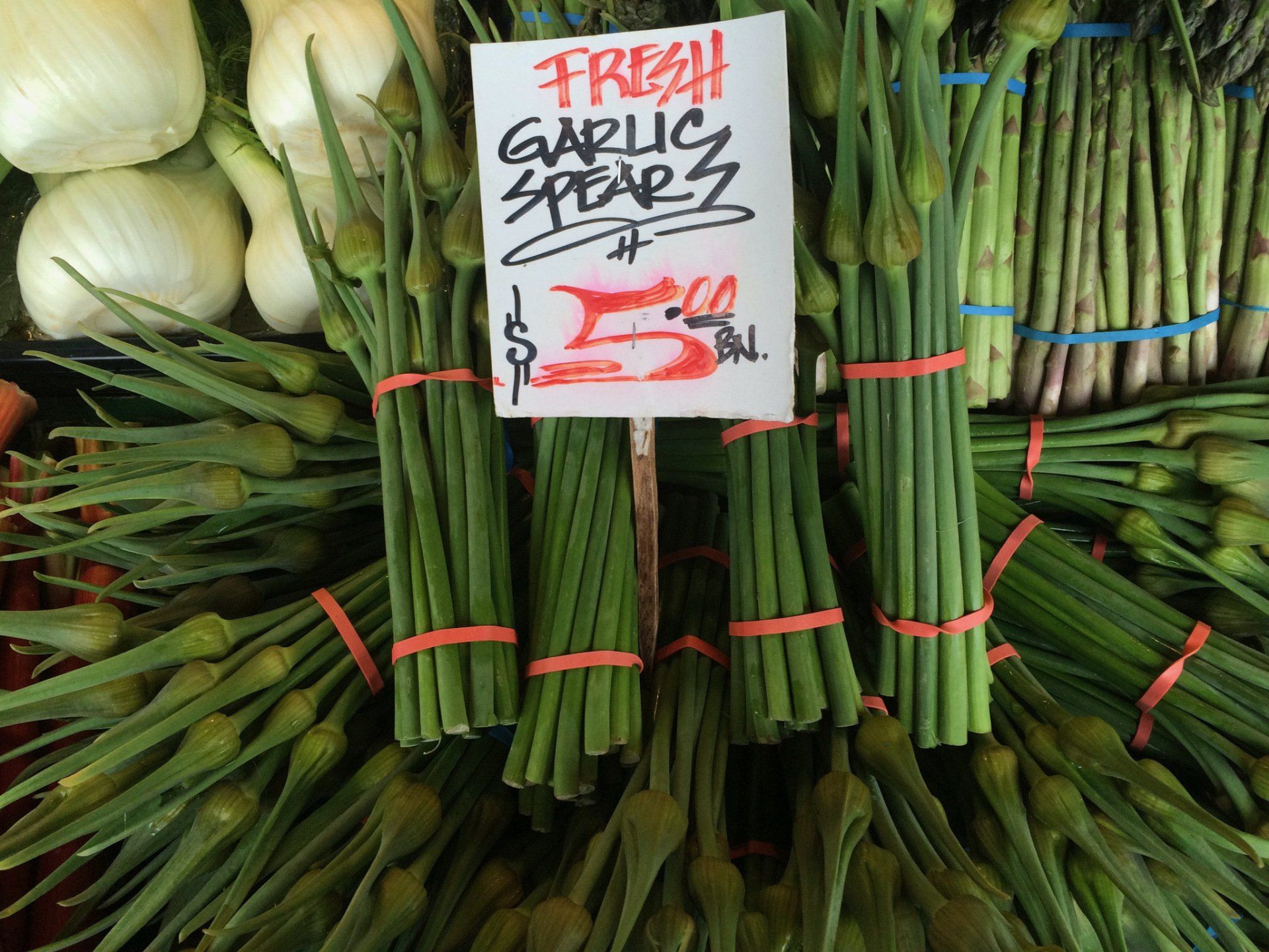 A bunch of garlic spears are for sale for 5 cents