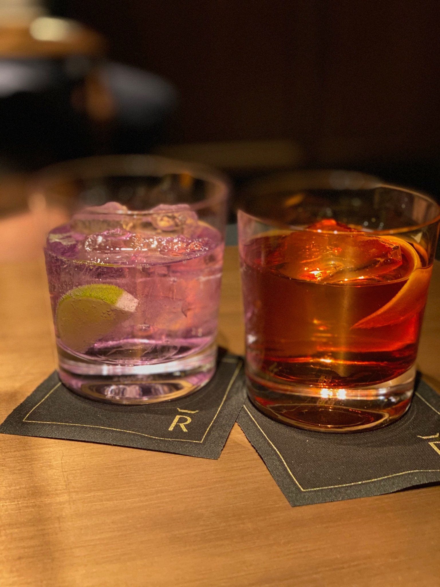 Two glasses of alcohol are sitting on a wooden table.