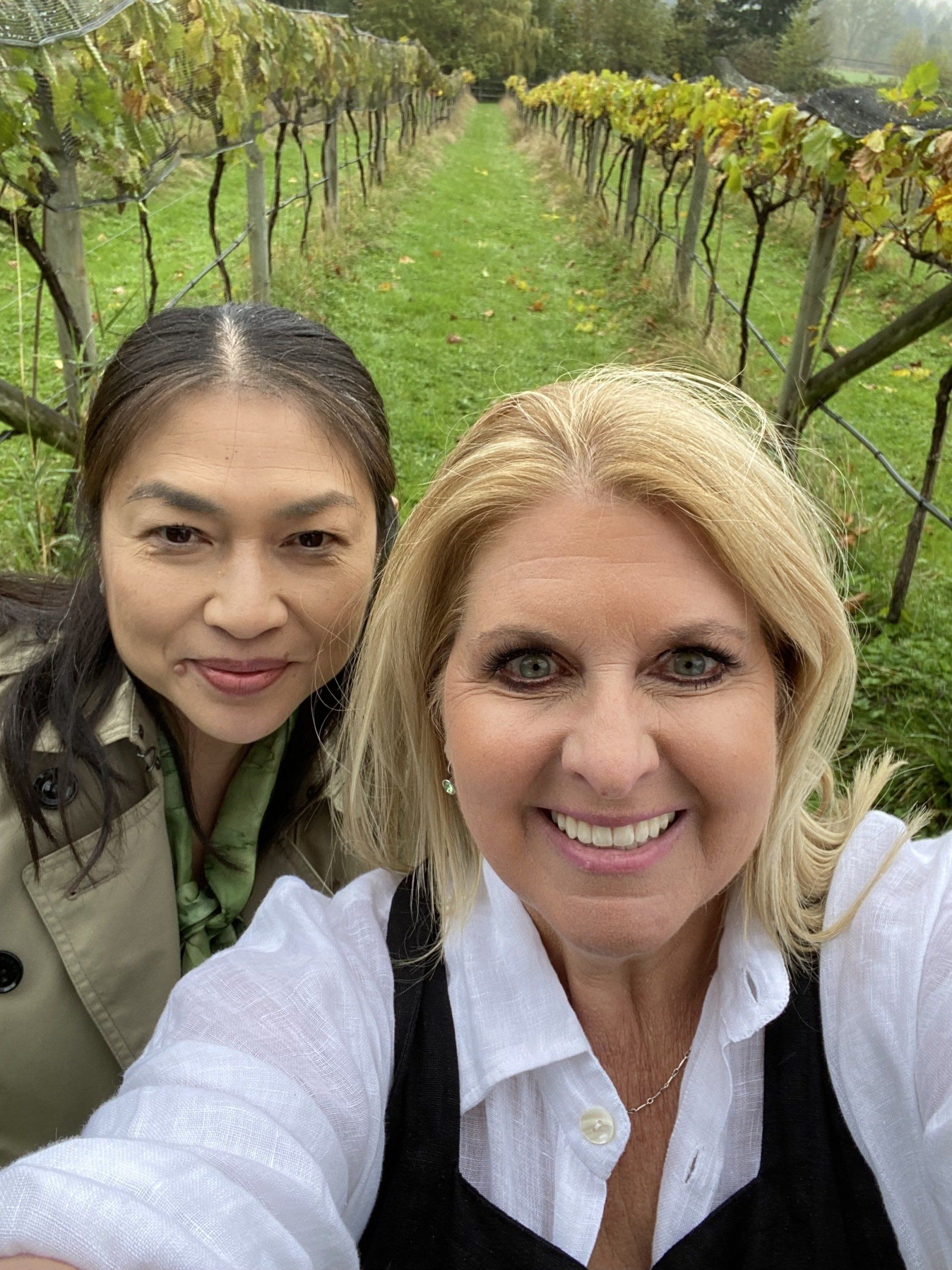 Two women are taking a selfie in a vineyard.