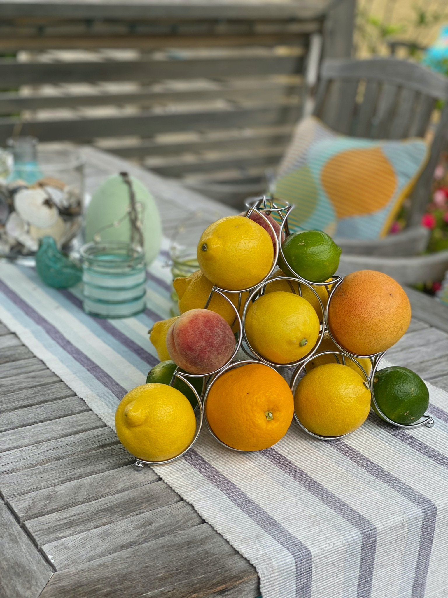 A stack of lemons , oranges , peaches and limes on a table.