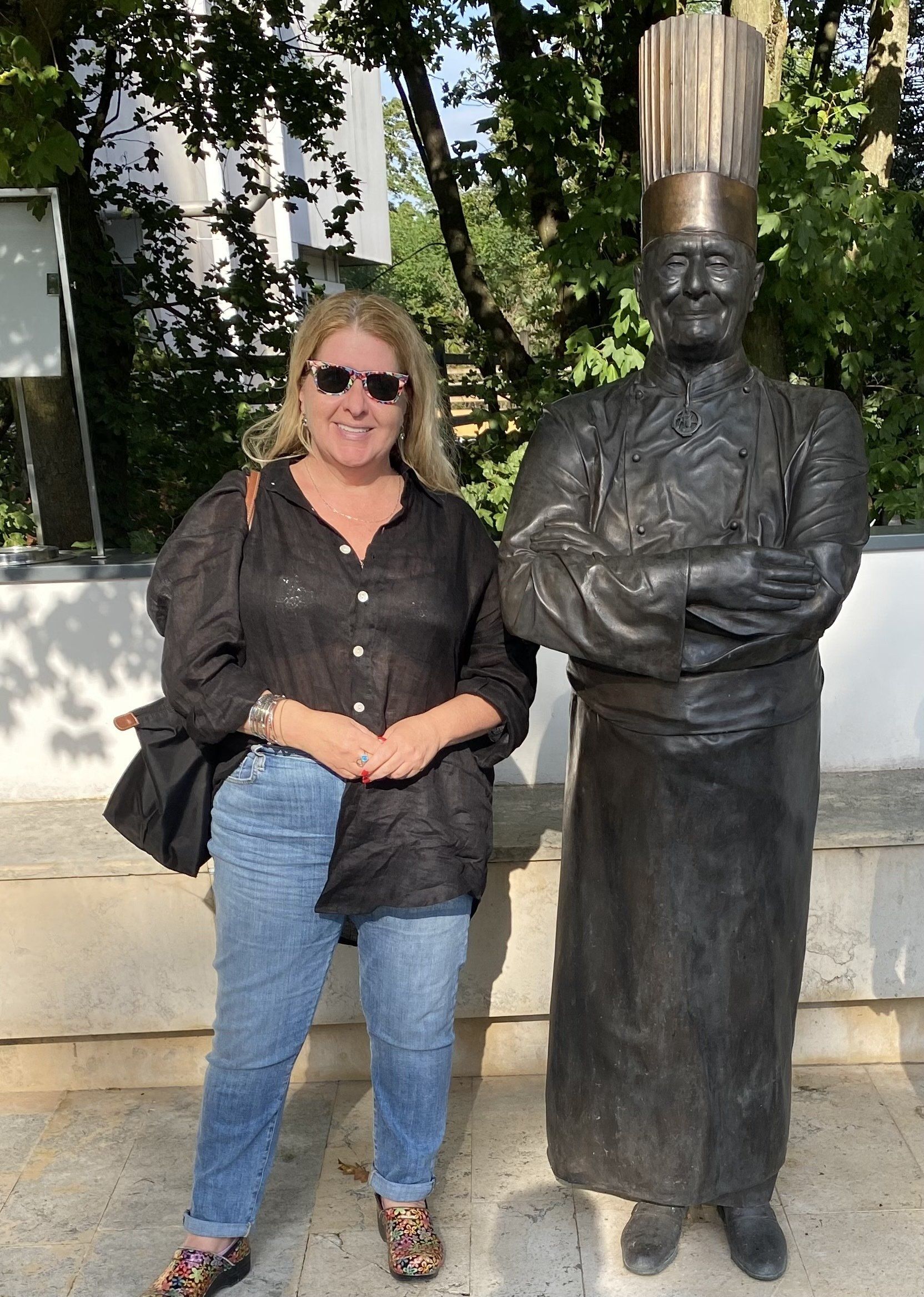A woman is standing next to a statue of a chef.