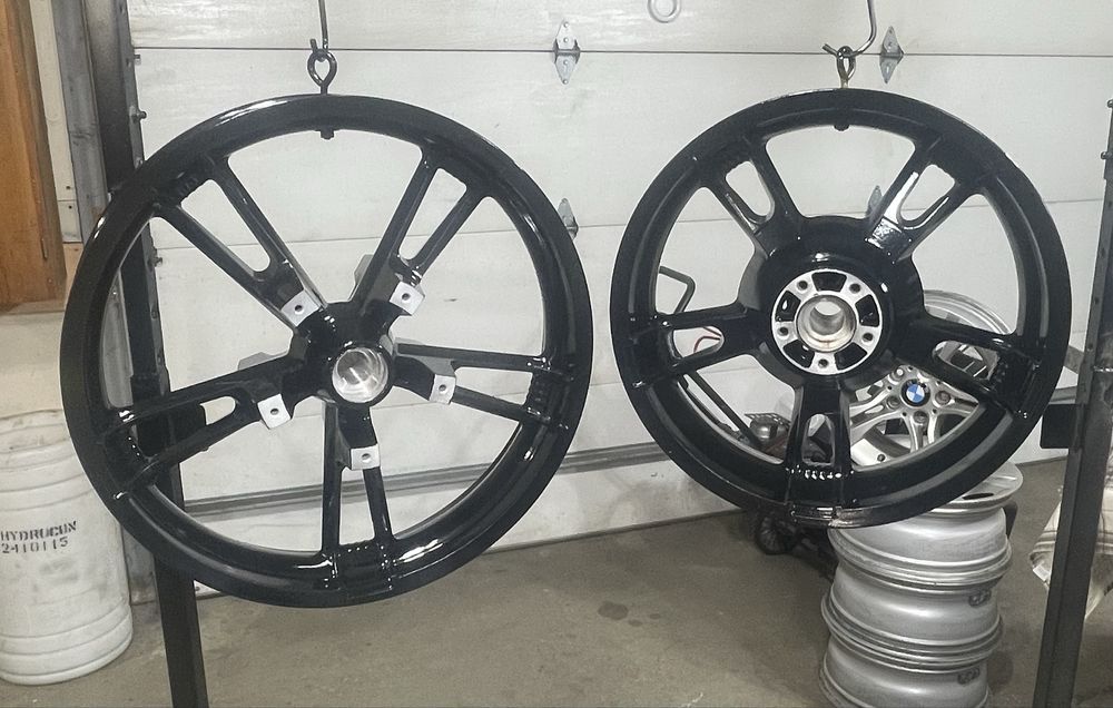 Two black car rims hanging in a garage, against a white garage door.