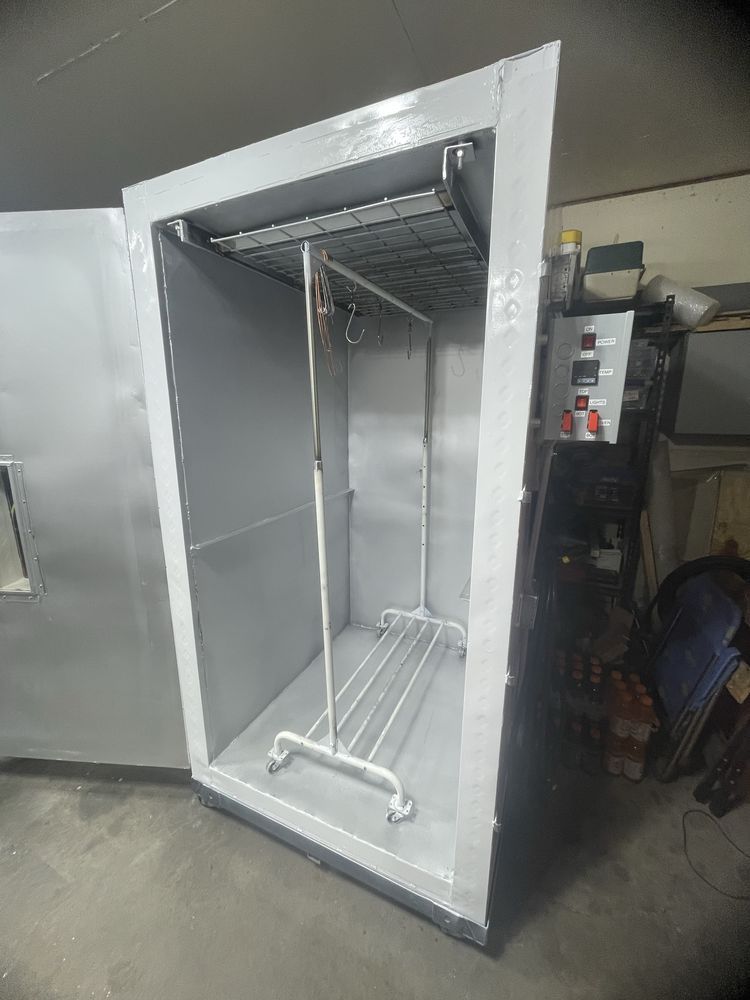 A gray metal drying cabinet with an open door, clothes rack inside.