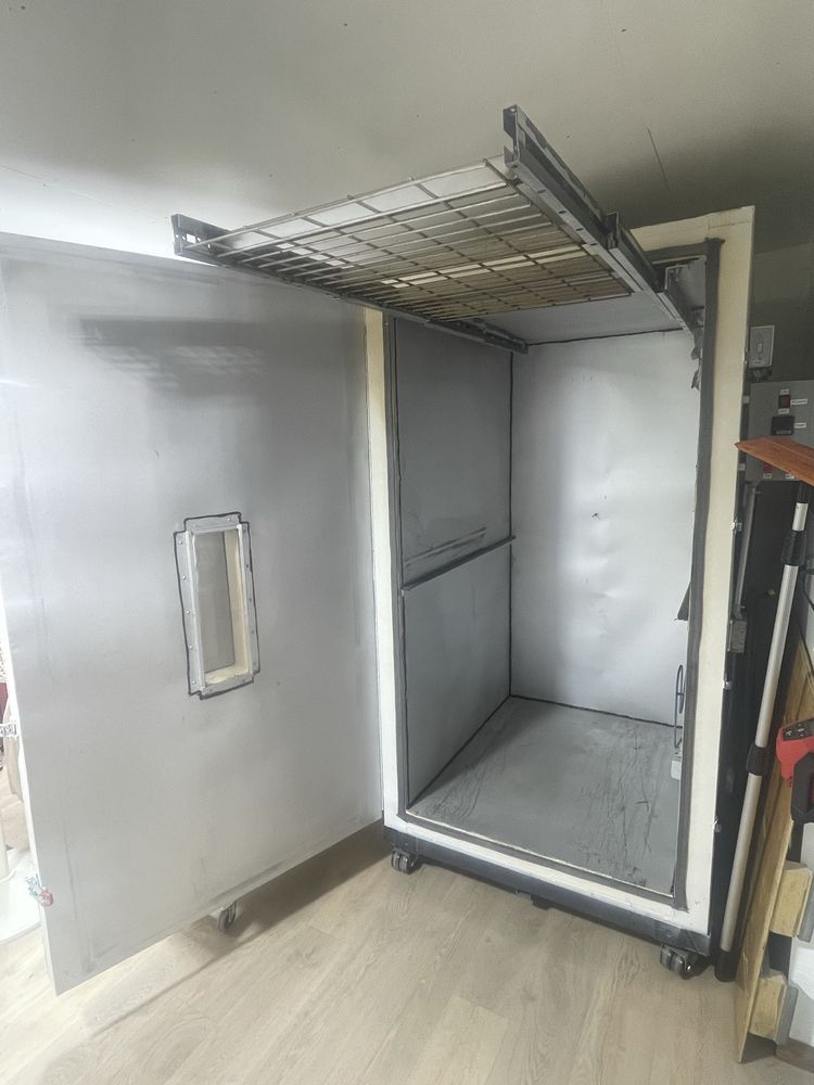 Open industrial metal cabinet with a door ajar, interior visible, and a rack at the top.