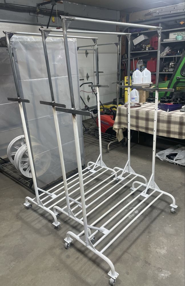 White metal clothing racks on wheels in a garage.