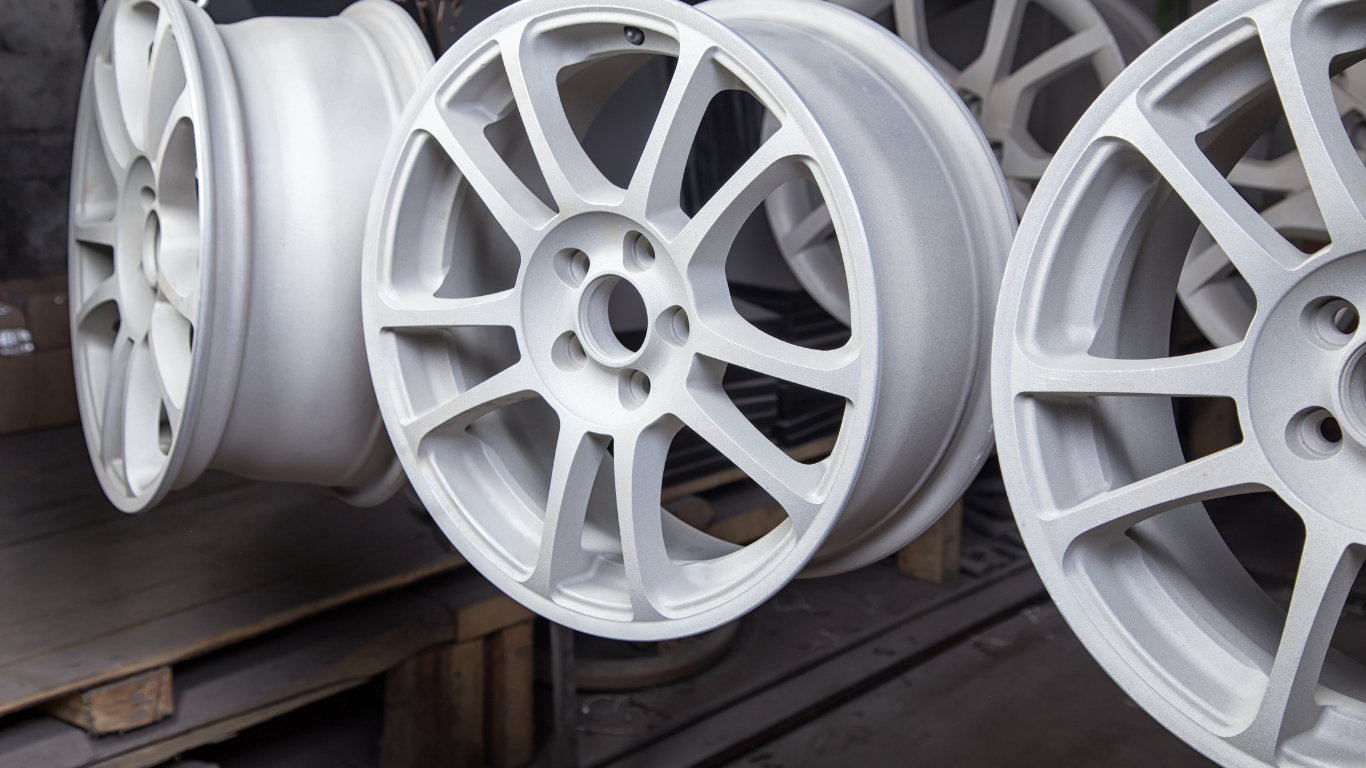 Silver-painted car wheels hanging on a rack inside a workshop.