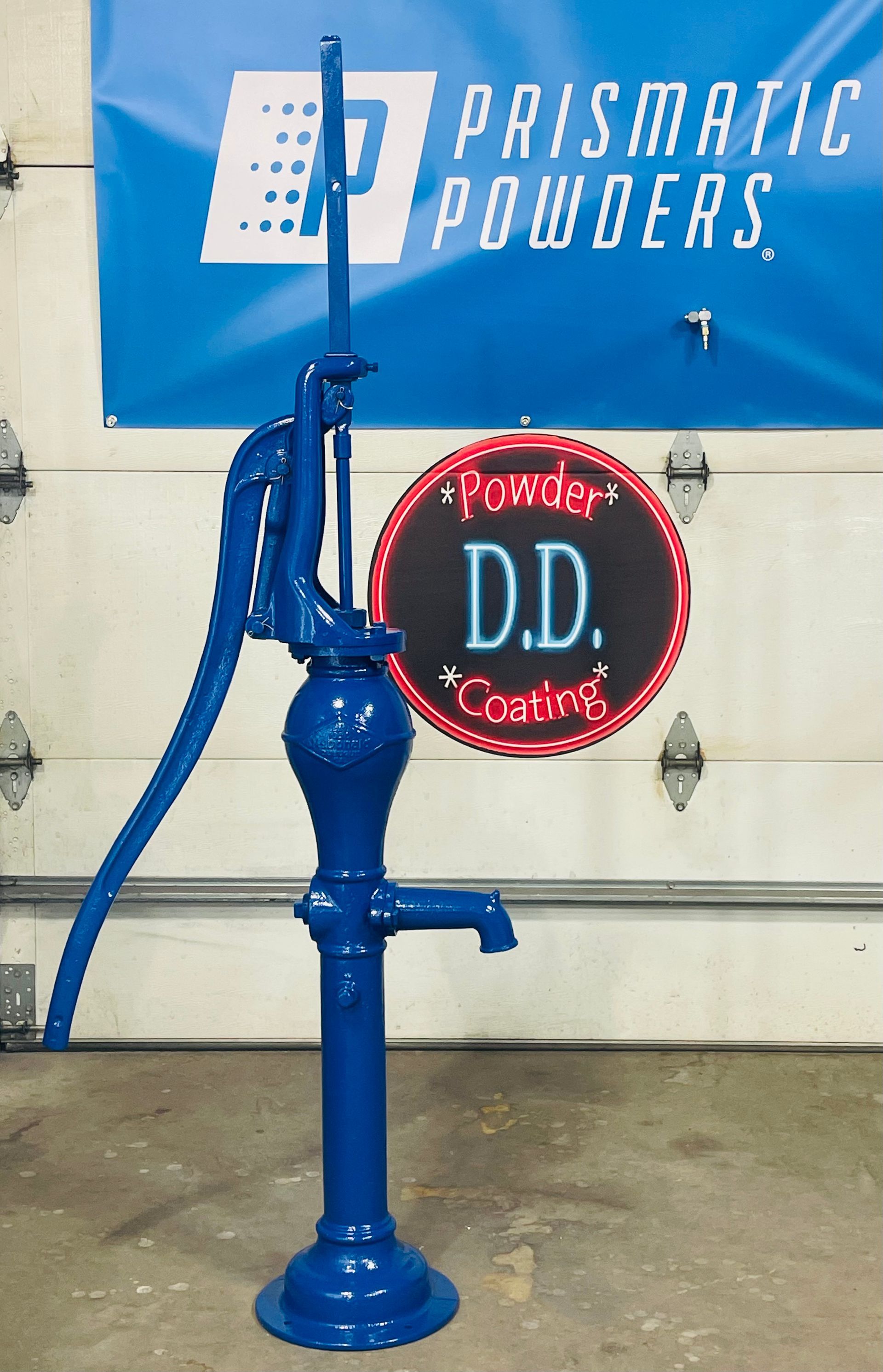 A bright blue antique water pump stands in front of a 