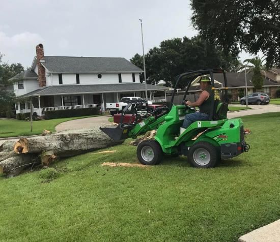 A man is driving a green tractor in front of a house.