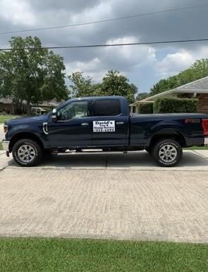 A blue pickup truck is parked in a driveway next to a house.