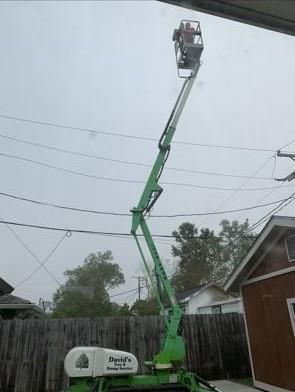 A green aerial lift is sitting in front of a house.