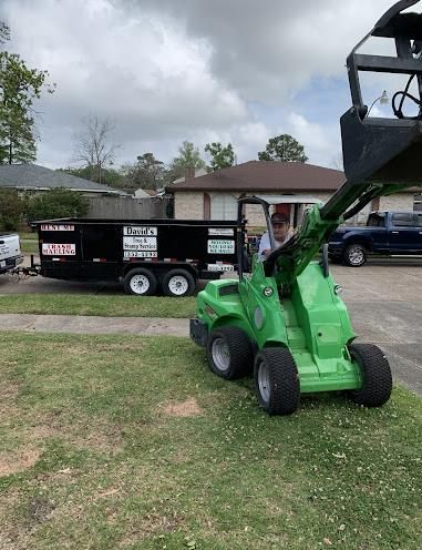 A man is driving a green tractor next to a dumpster.