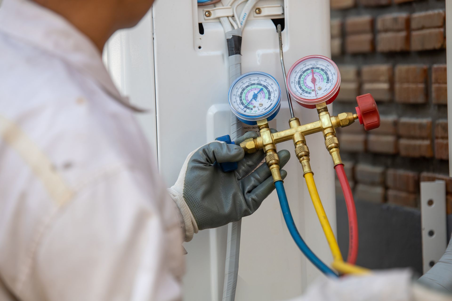 Technician using gauges to service an air conditioning unit.