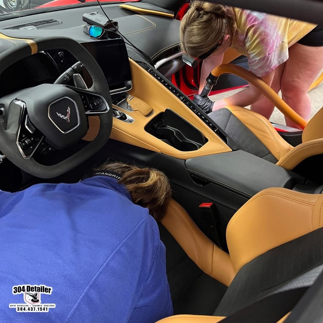 A woman is cleaning the interior of a car with a vacuum cleaner