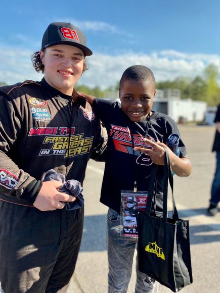 Two young boys are posing for a picture in a parking lot.