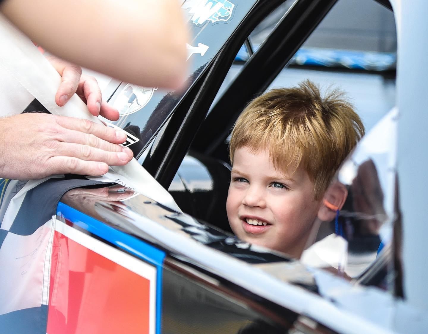 A young boy is looking out the window of a race car