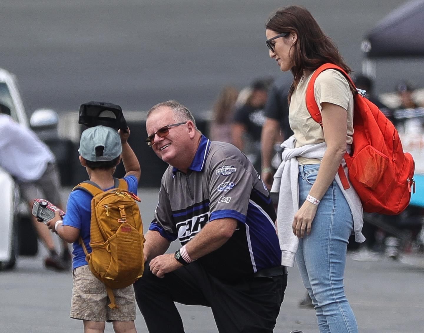 A man and a woman are talking to a little boy with a backpack.