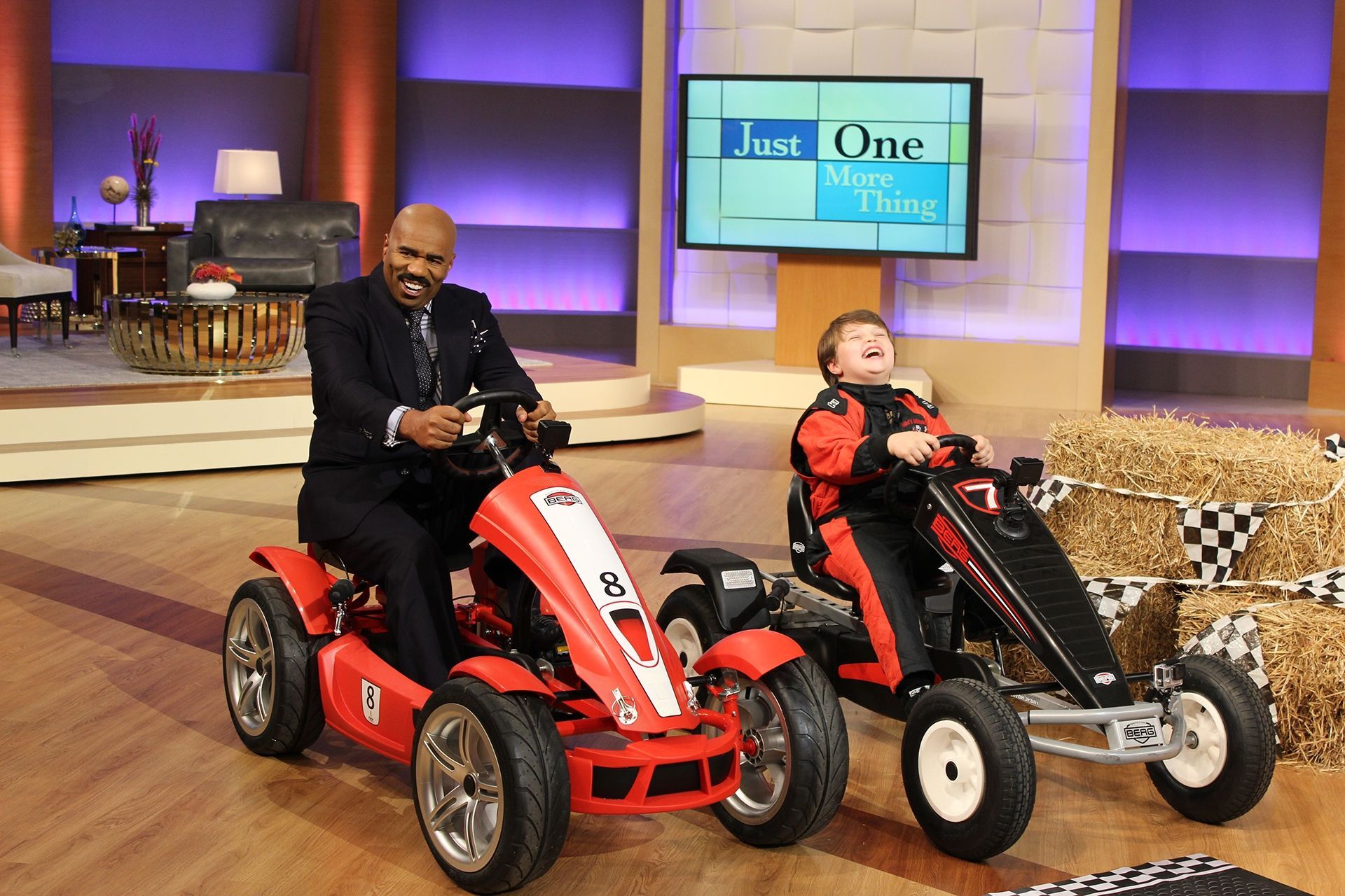 A man and a boy are riding go karts on a stage.