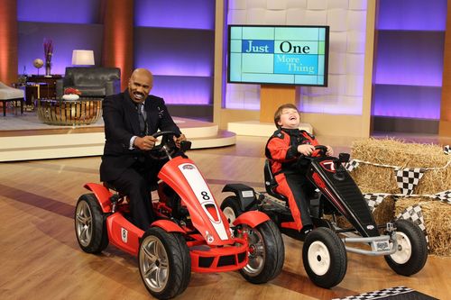 A man and a boy are riding go karts on a stage.