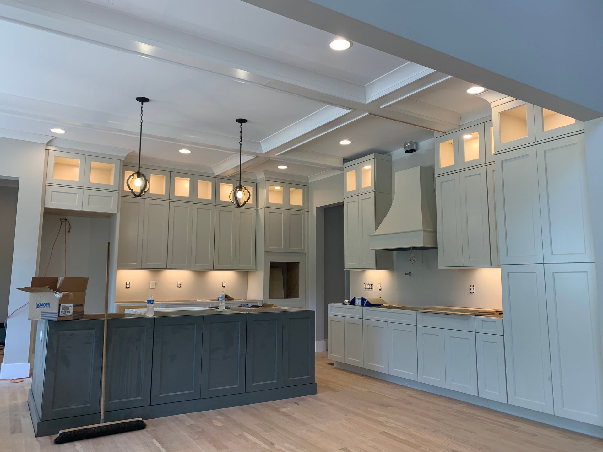 Kitchen under construction with grey island, and white cabinets.