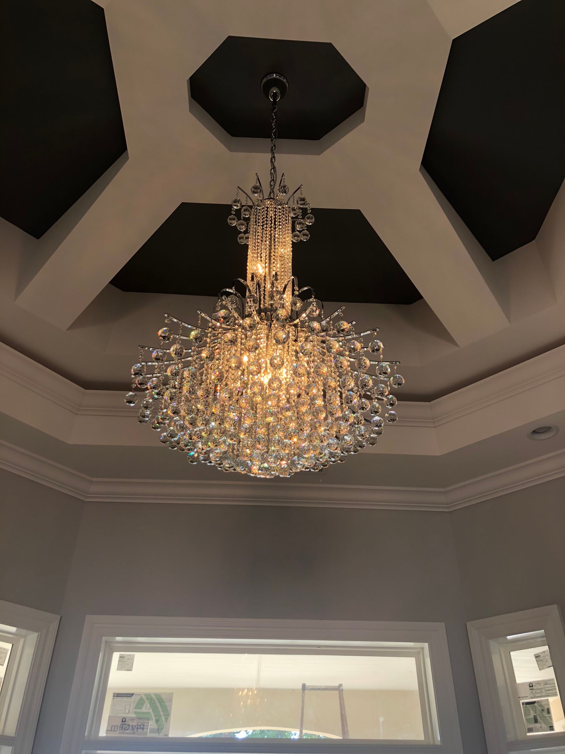 Crystal chandelier hanging from a dark ceiling accent in a room.