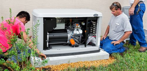 Three workers installing a generator near a house.