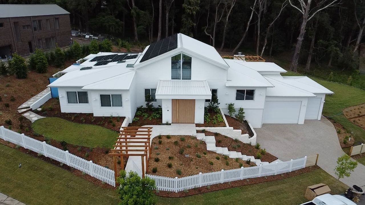 A Person Is Cleaning A Window With Pressure Washer — Jervis Bay Pressure Washing & Property Maintenance In Sussex Inlet, NSW