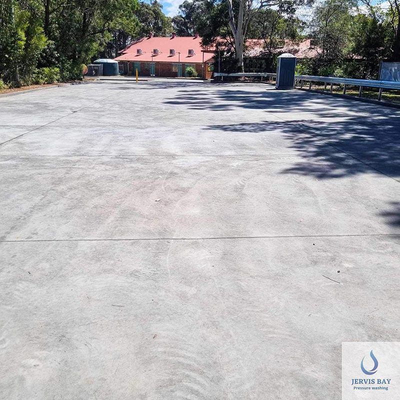 Large Concrete Driveway With A Red House In Background — Jervis Bay Pressure Washing & Property Maintenance in Culburra, NSW