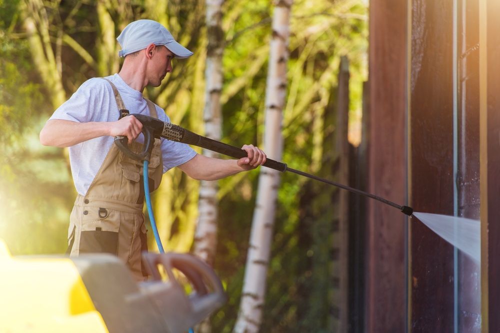 A Man Is Using Pressure Washer To Clean A Building — Jervis Bay Pressure Washing & Property Maintenance In Jervis Bay, NSW