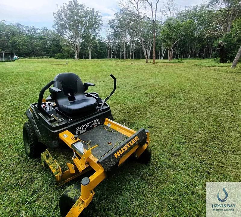 A Lawn Mower Is Parked On A Lush Green Field — Jervis Bay Pressure Washing & Property Maintenance in Sanctuary Point, NSW