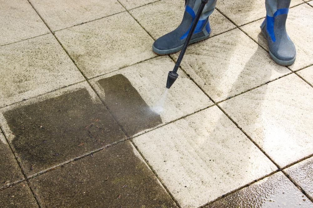 A Person Is Cleaning A Tiled Floor With A Pressure Washer — Jervis Bay Pressure Washing & Property Maintenance In Berry, NSW