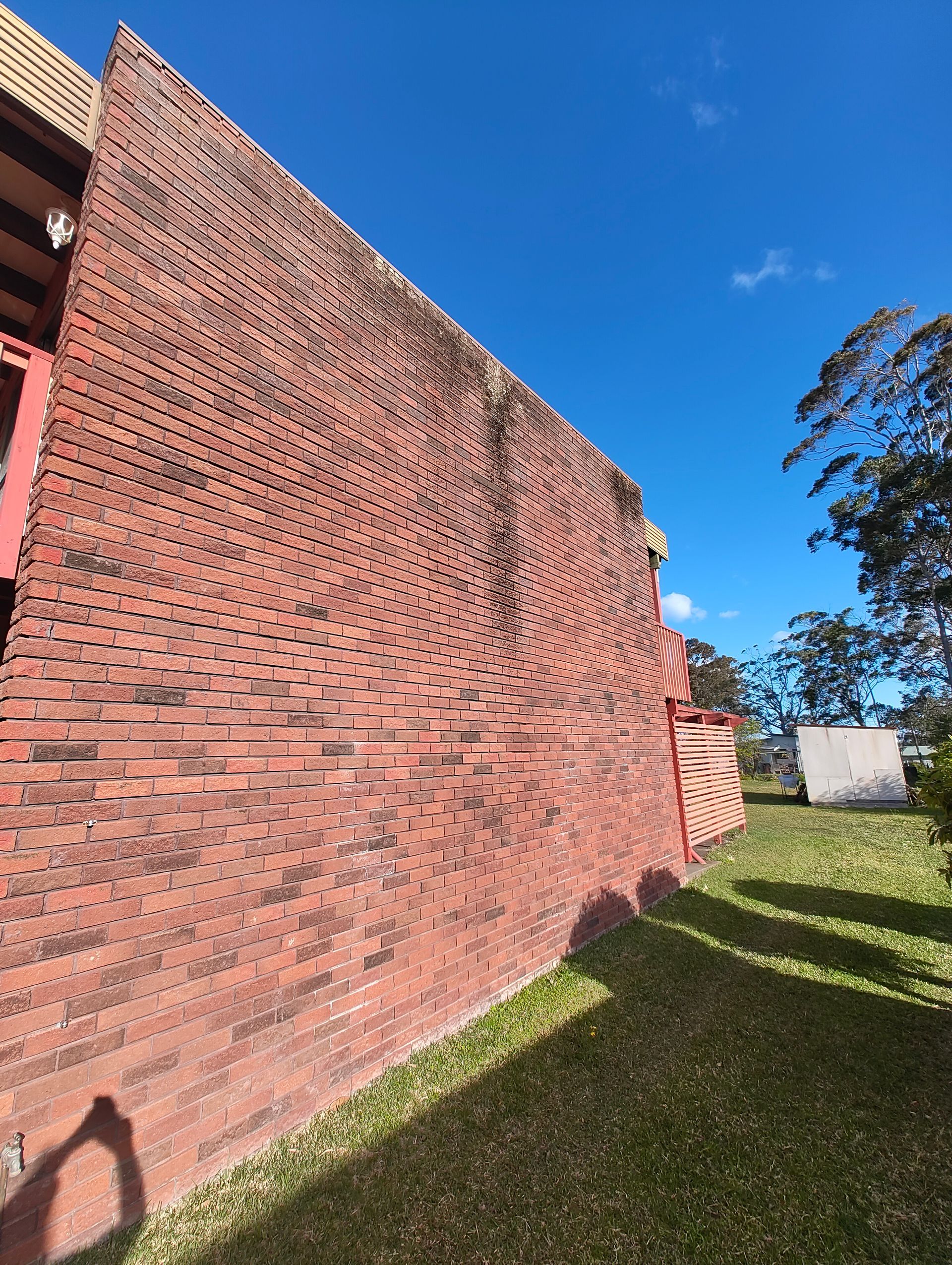 Dirty Red Brick Wall With A Blue Sky Background — Jervis Bay Pressure Washing & Property Maintenance in Sanctuary Point, NSW