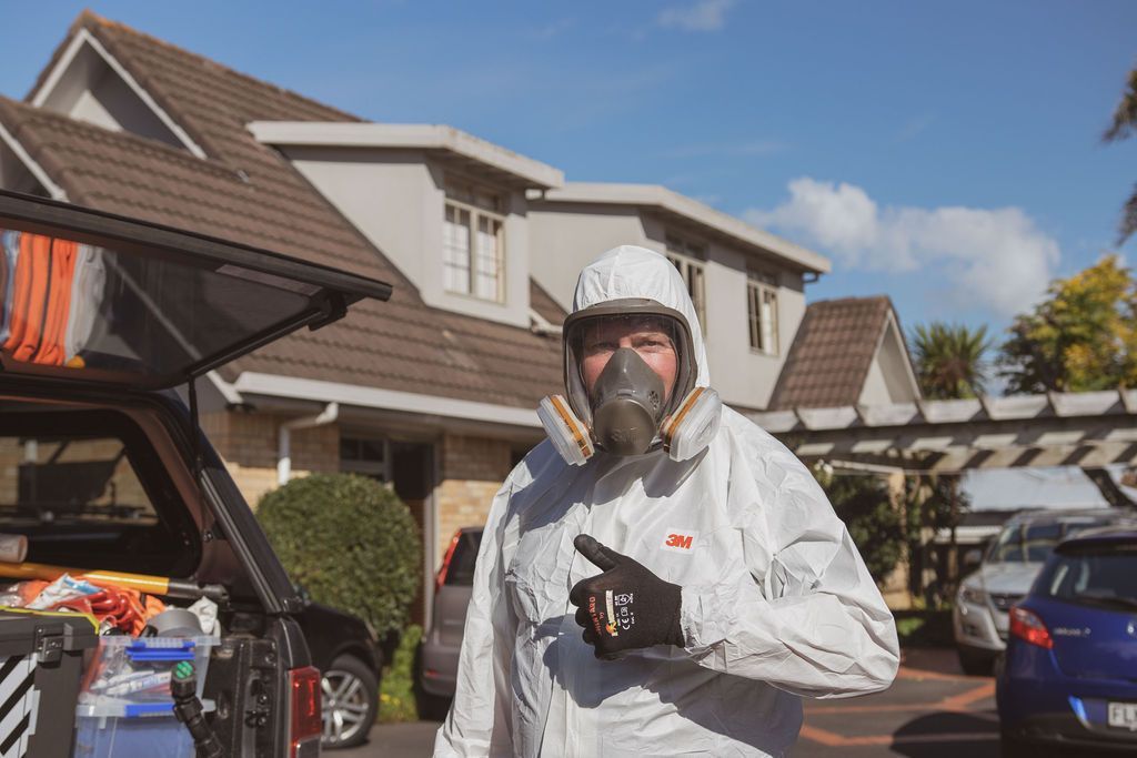 Stu & Duncan wearing a gas mask is standing in front of a house.