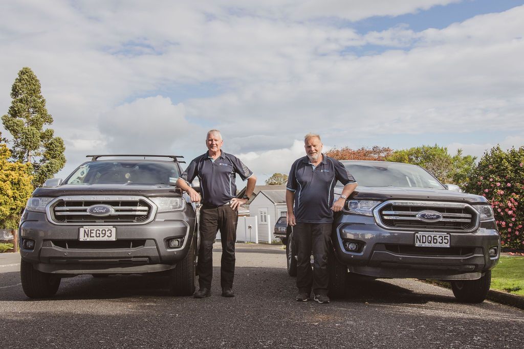 Stu & Duncan  are standing next to each other in front of two ford trucks.