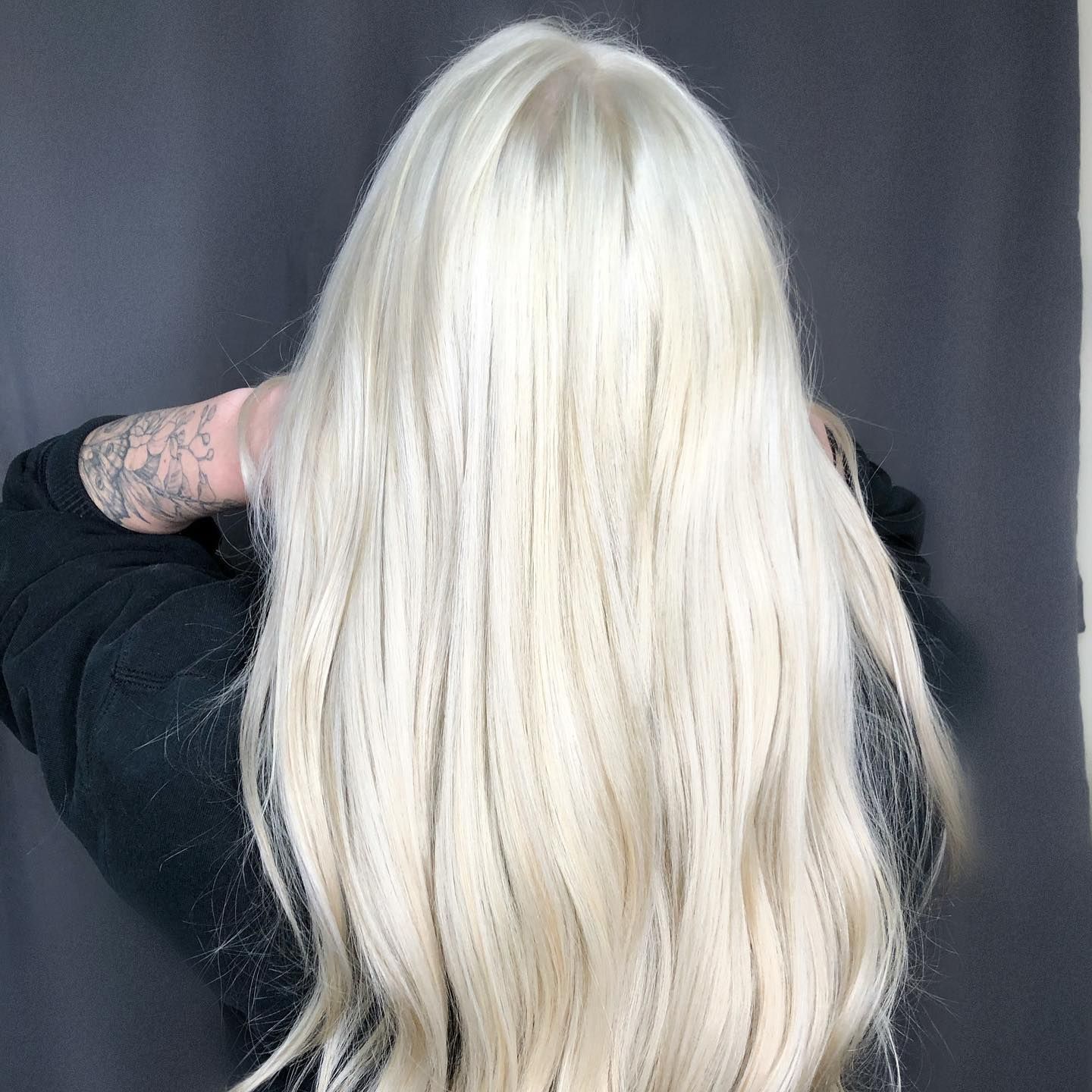 Person with long, platinum blonde hair, back to the viewer; wearing a black top.