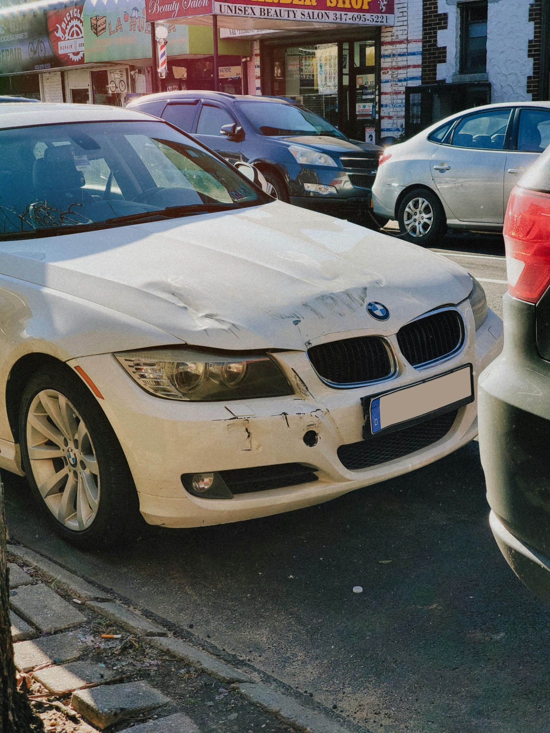 White BMW sedan parked on a city street beside other cars and storefronts