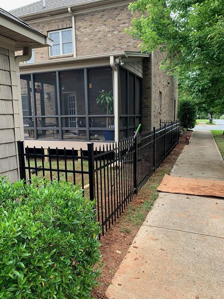 Apartment walkway beside screened porch and black fence along a sidewalk.