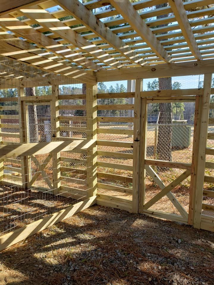 Wooden chicken coop with slatted walls and roof, sunlight casting shadows inside and outside.