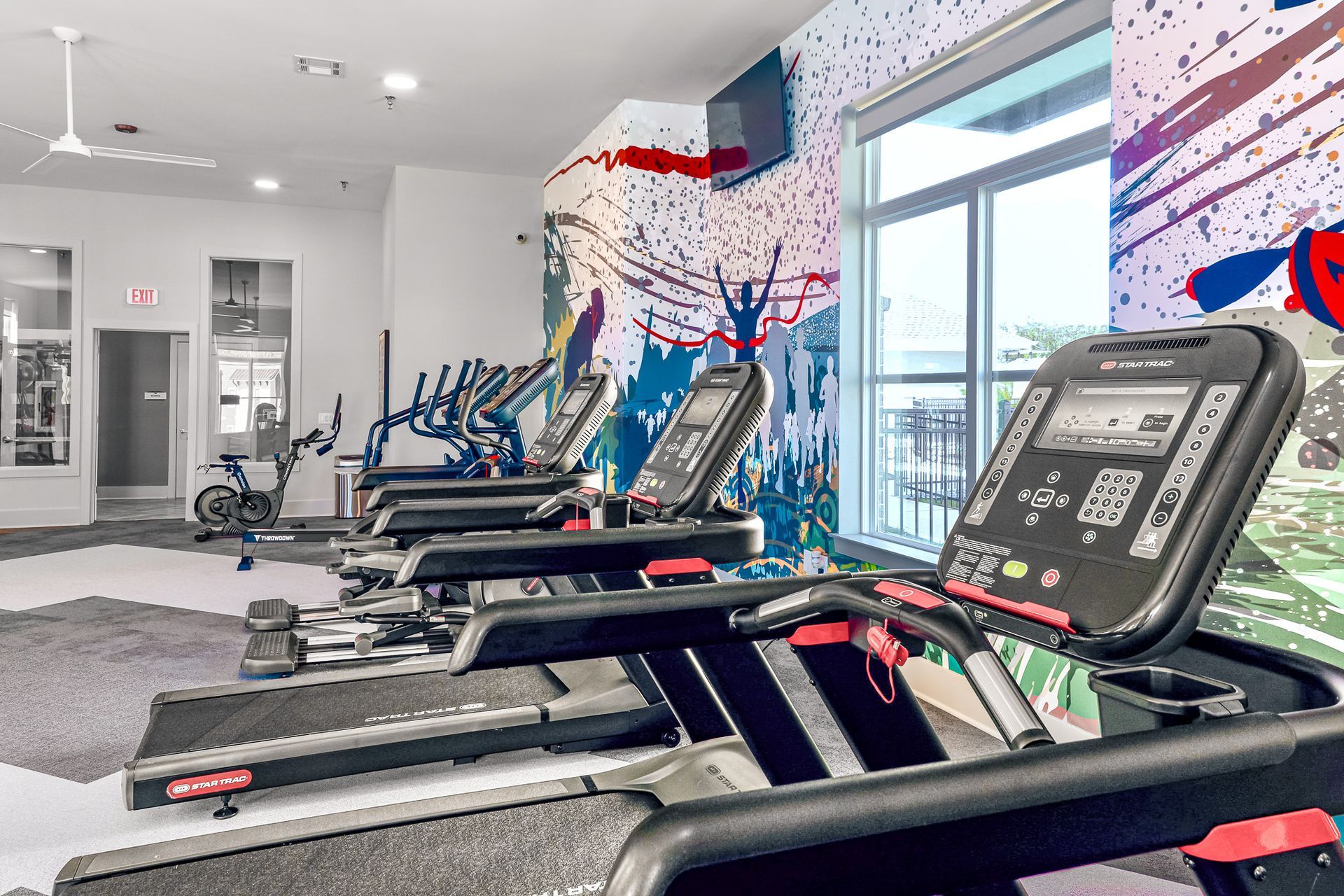 Modern kitchen with white cabinets, stainless steel appliances, and a gray countertop island with blue bar stools.