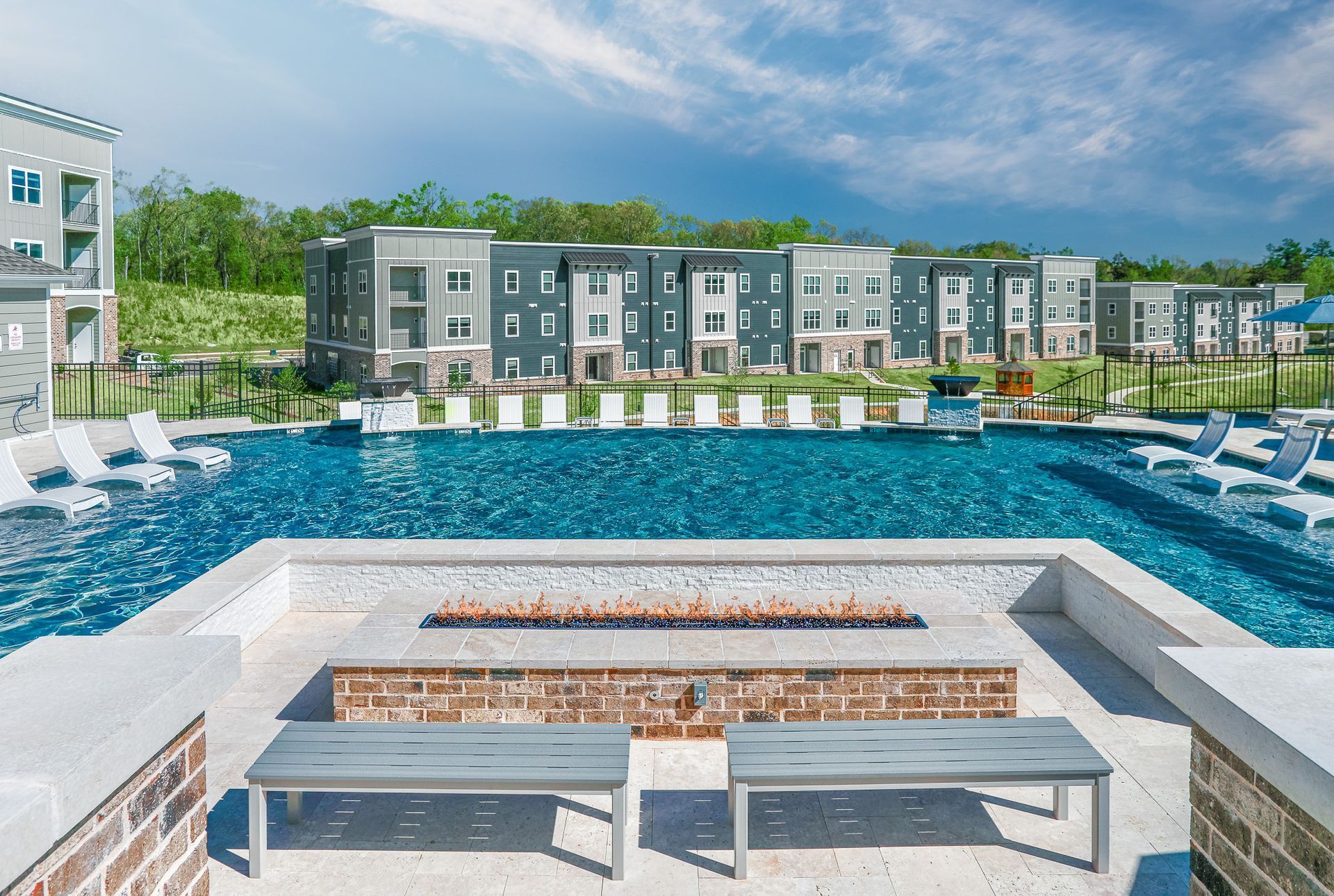 Modern kitchen with white cabinets, granite island, stainless steel appliances, and blue bar stools.