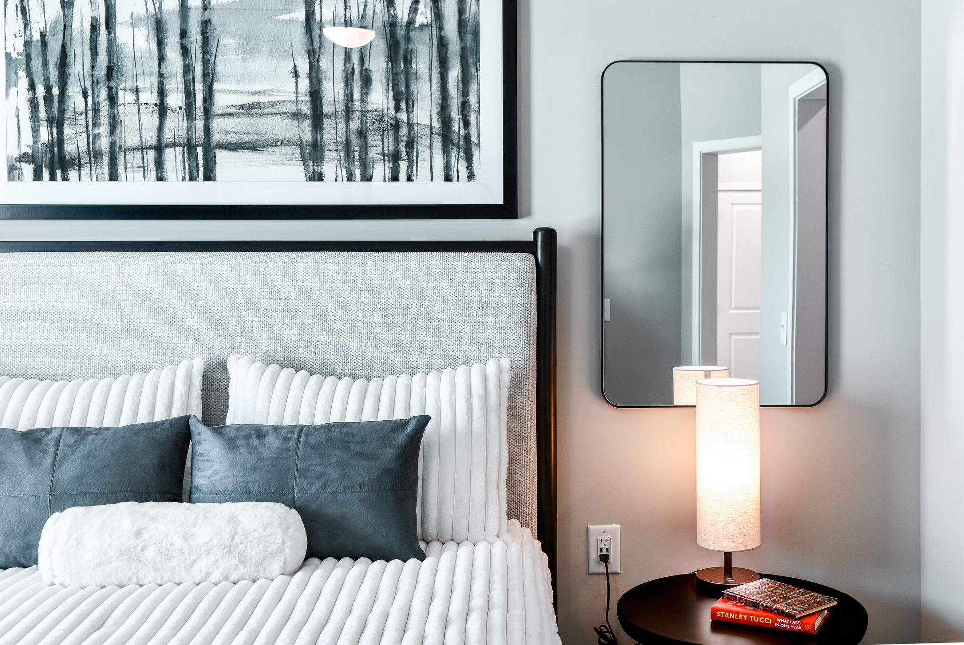Three people sitting at a picnic table in a park, under trees on a sunny day.