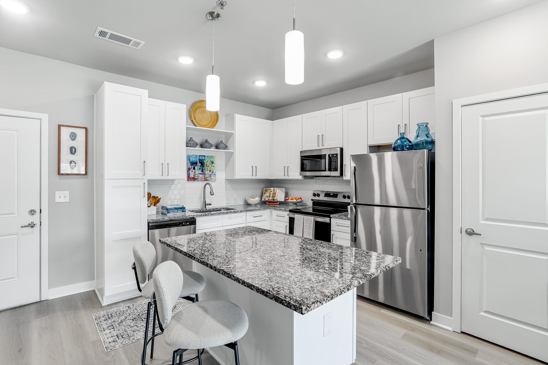 Bedroom with a large bed, nightstands, closet, artwork, and a ceiling fan; light colors.
