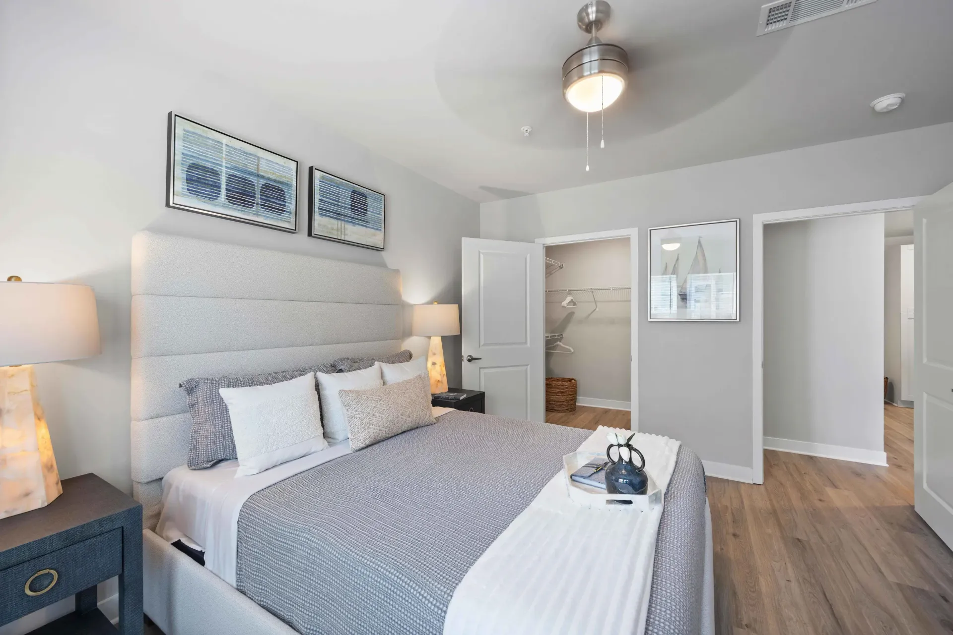 Bedroom with a bed, dresser, chair, and two windows. Gray and blue color scheme.