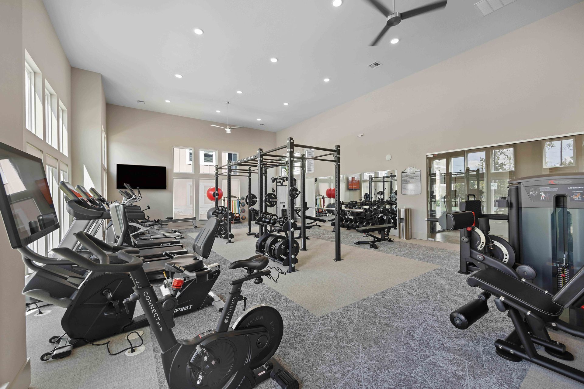 Modern kitchen with white cabinets, stainless steel appliances, and a gray countertop island with blue bar stools.