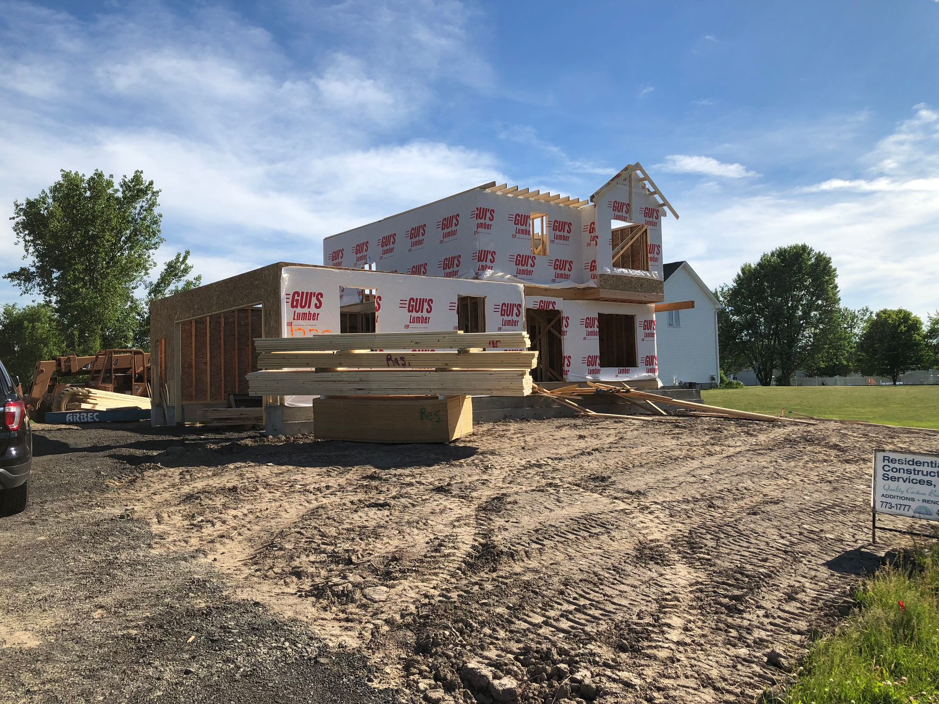 House under construction, wooden frame, blue sky, unfinished roof, windows.