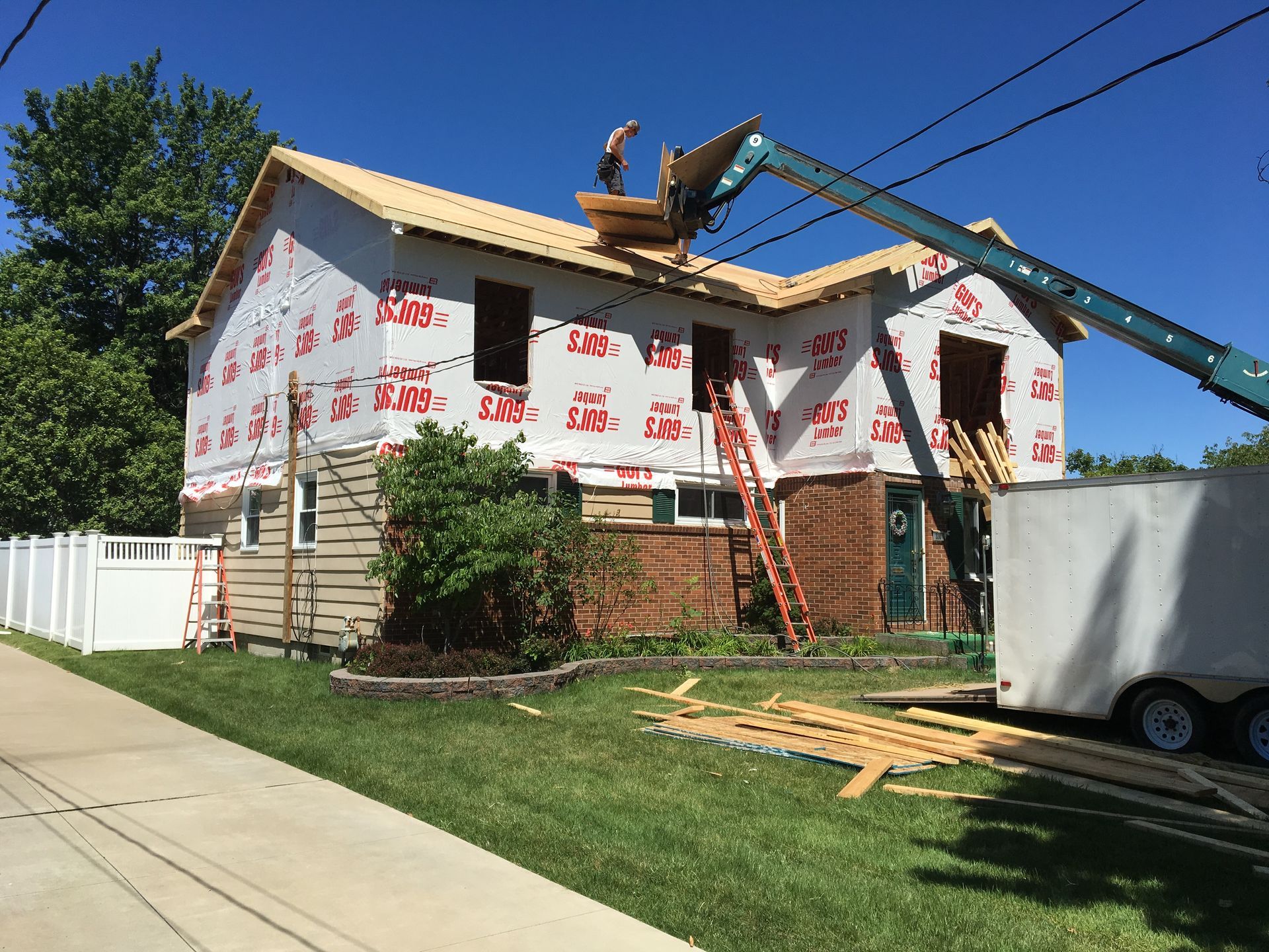 House under construction with exposed wooden frame against a cloudy blue sky.
