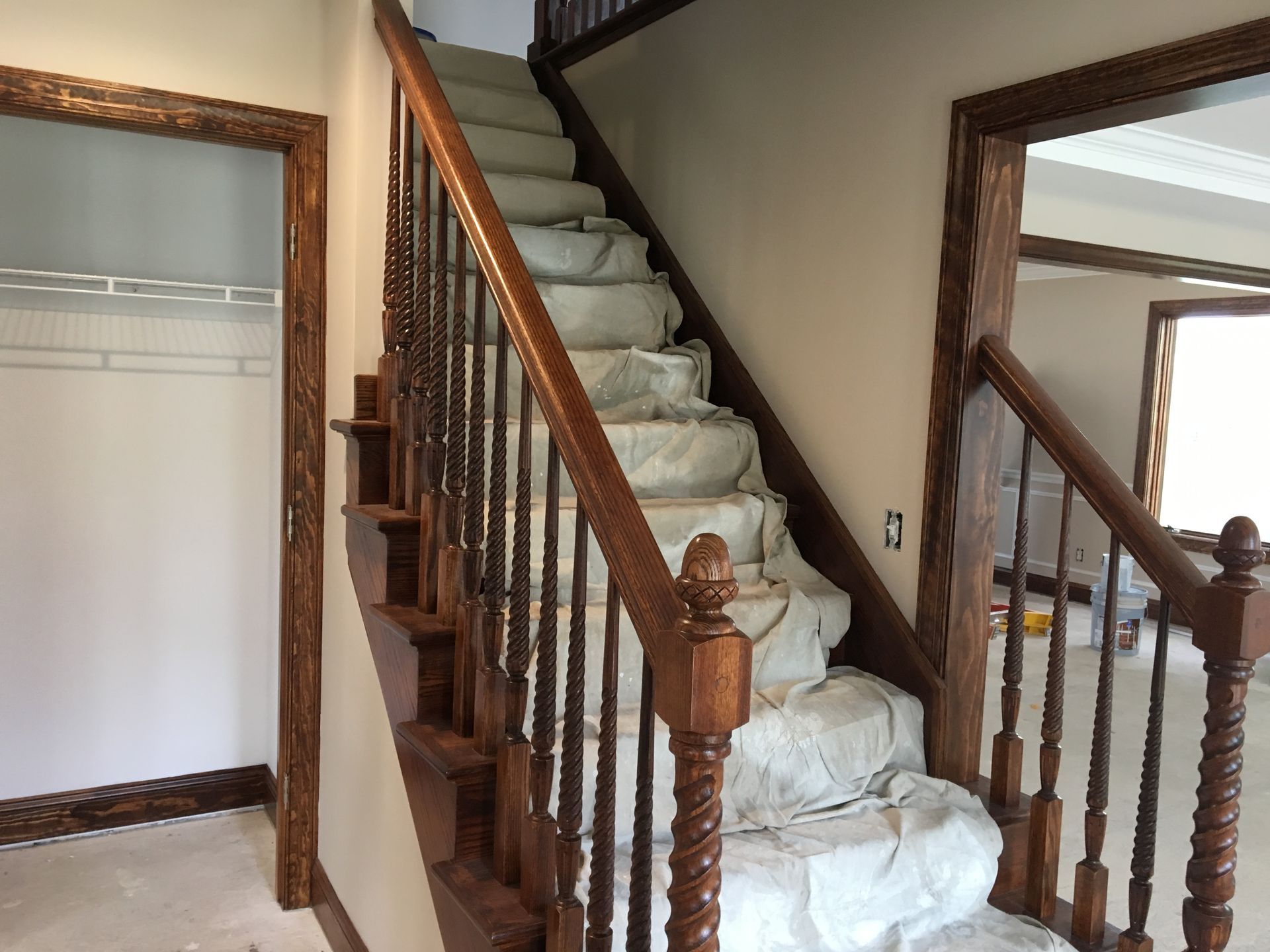 Construction site with unfinished house; stacked lumber and green boards in front.