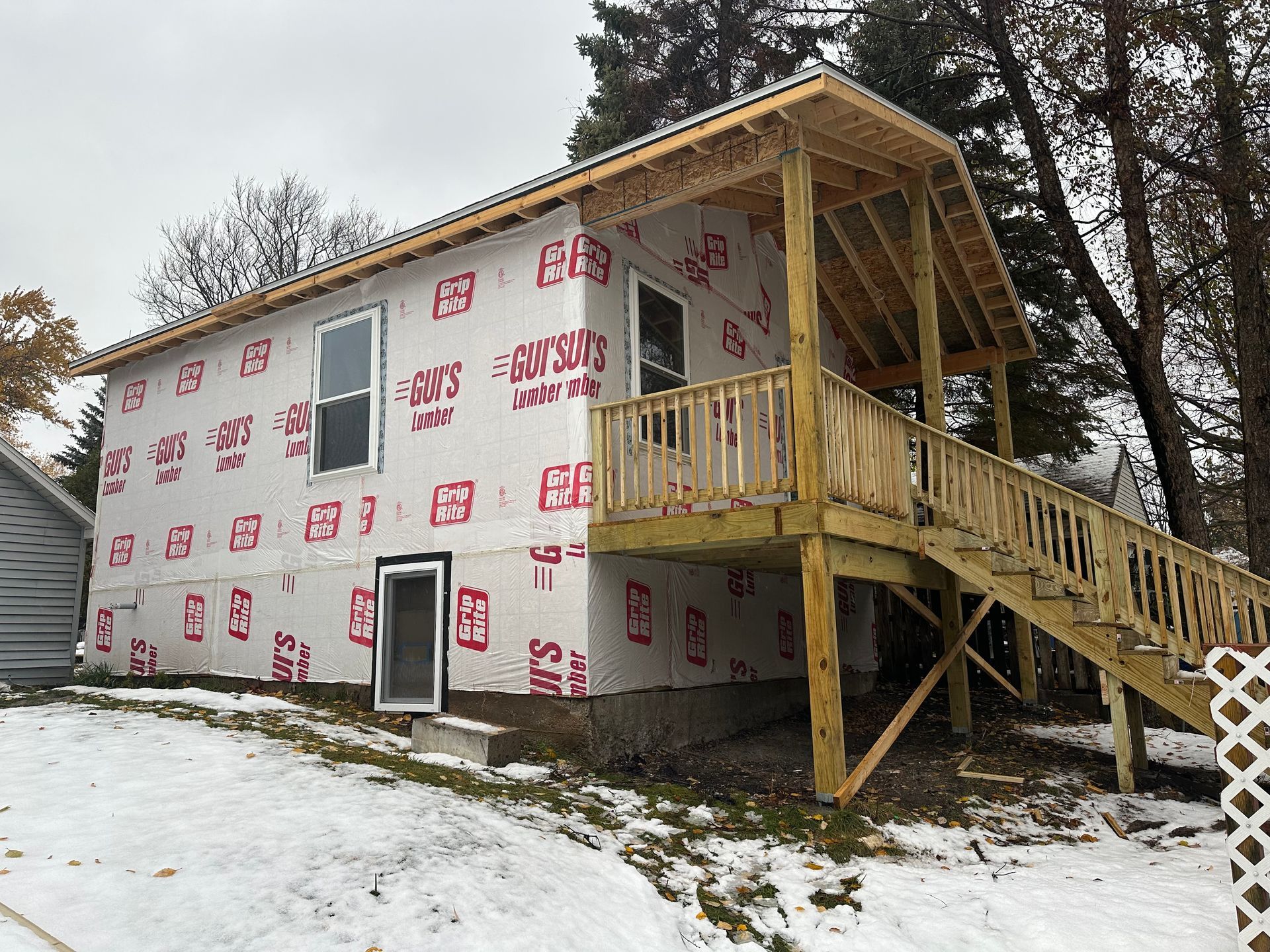 Unfinished basement with concrete floor, exposed beams, water heater, and stairs leading up.