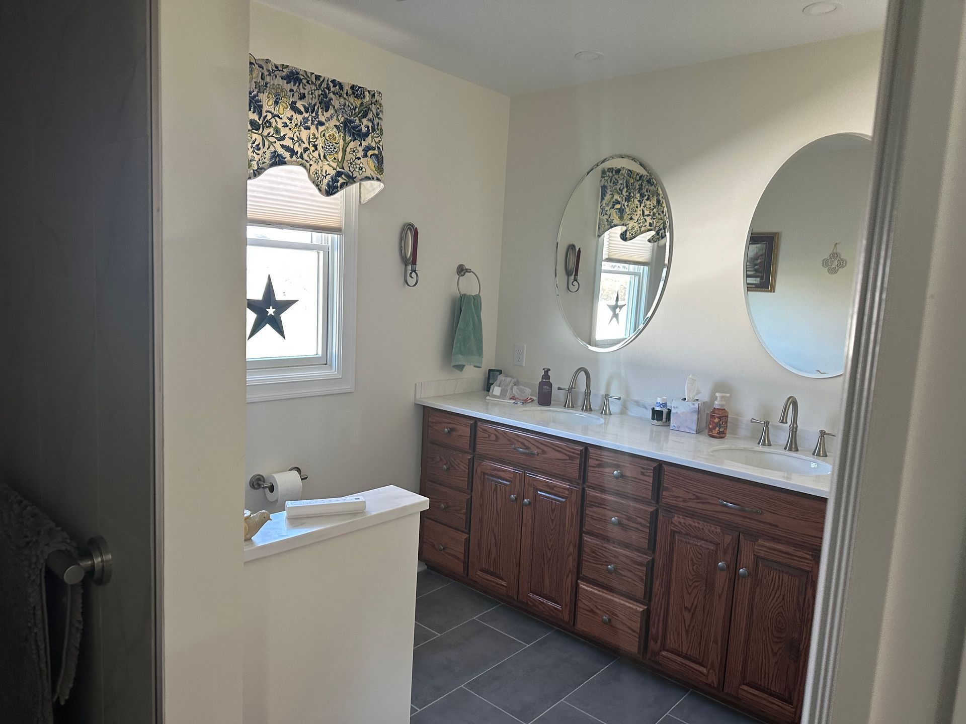 Modern bathroom with white marble walls, blue vanity, and a black-framed shower.