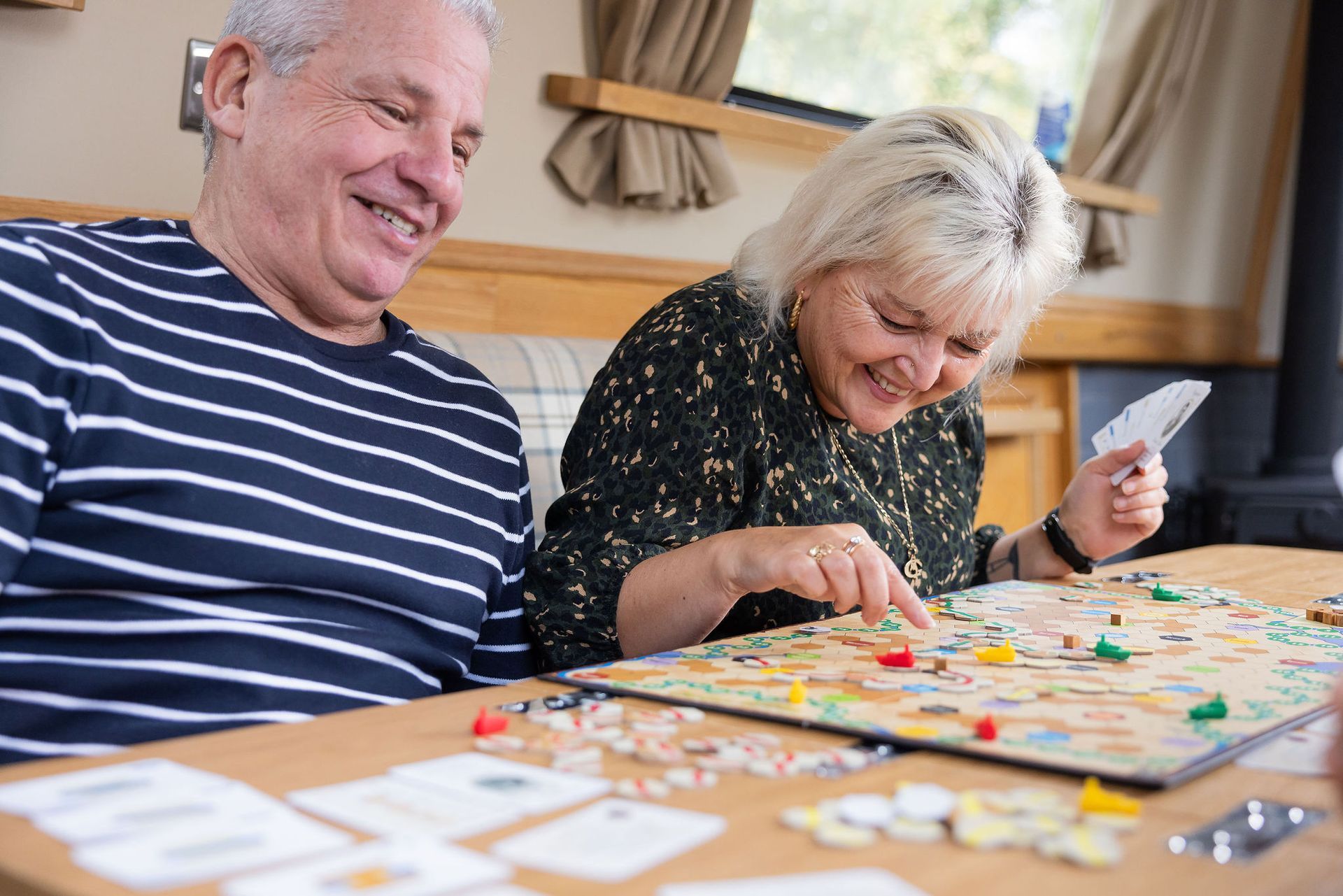 A man and a woman are sitting at a table playing a board game.